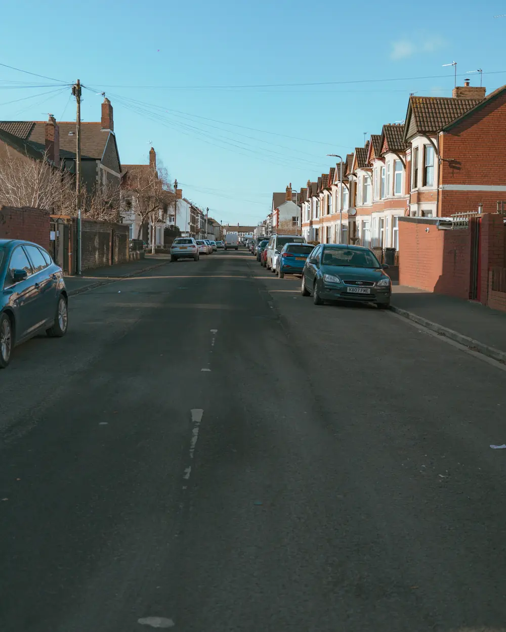 A street of red-brick terraced houses on a clear day