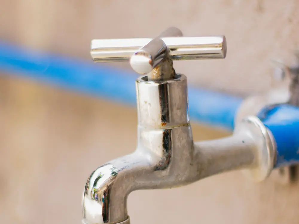 A chrome outside tap on a blue water pipe
