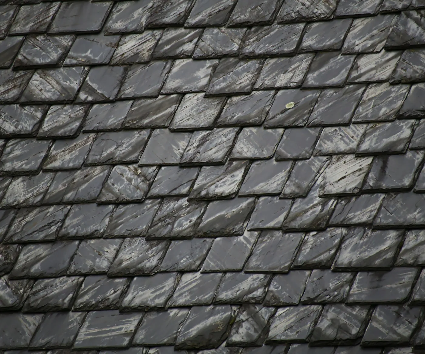 Close up of a wet slate roof, the slates laid in overlapping rows