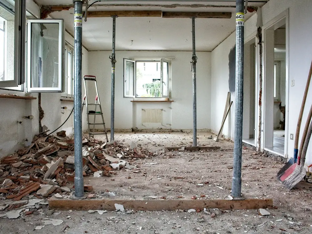 A room opened up into one space, its ceiling held on steel props over a floor of broken brick