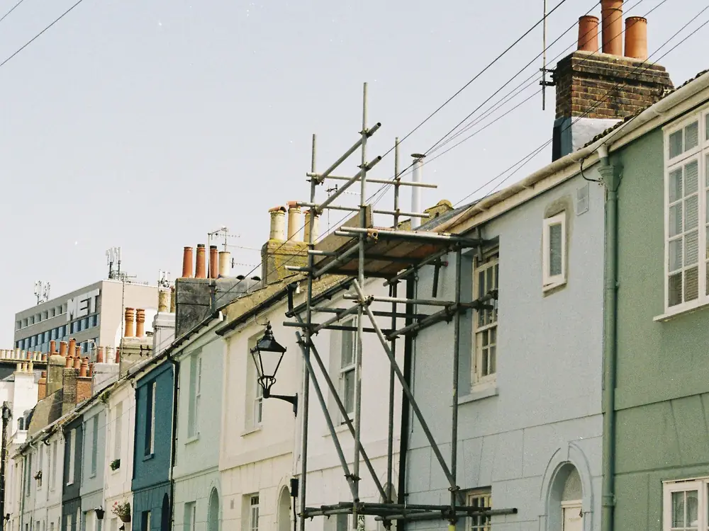 A row of terraced houses with scaffolding up the front of one of them